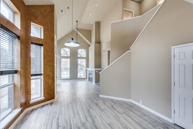 foyer with ceiling fan, a towering ceiling, and light hardwood / wood-style floors