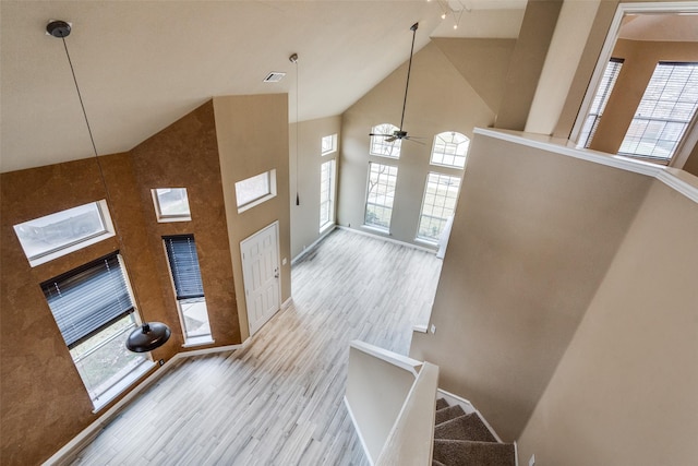 foyer featuring ceiling fan, a healthy amount of sunlight, high vaulted ceiling, and light hardwood / wood-style flooring