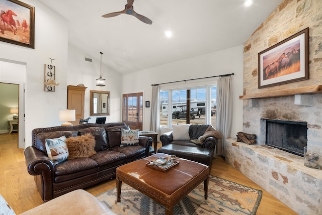 living room with ceiling fan, high vaulted ceiling, a fireplace, and light hardwood / wood-style floors