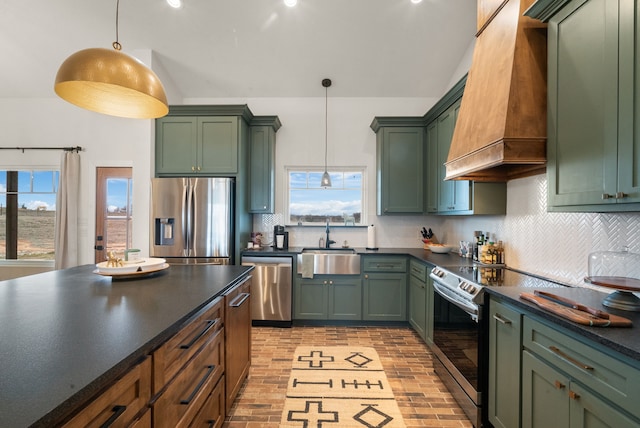 kitchen with pendant lighting, sink, stainless steel appliances, custom range hood, and green cabinetry