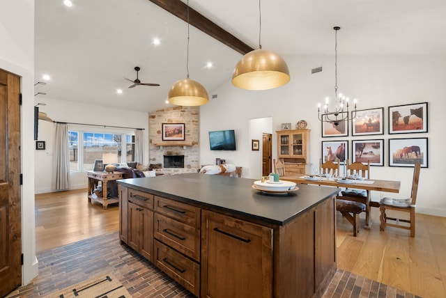 kitchen featuring beamed ceiling, a center island, hardwood / wood-style floors, and a fireplace