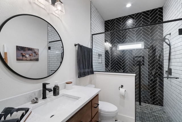 bathroom with vanity, tiled shower, and toilet