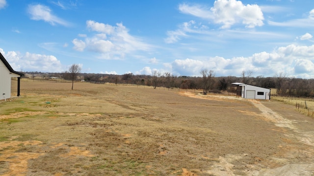 view of yard featuring a garage, an outdoor structure, and a rural view