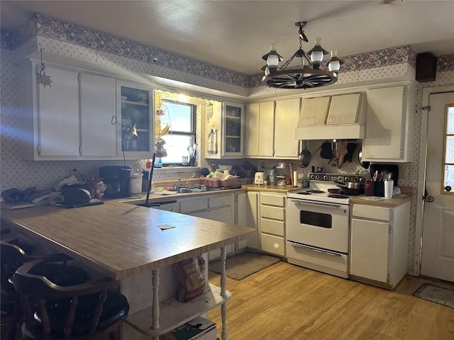 kitchen with white electric stove, white cabinetry, custom range hood, an inviting chandelier, and light hardwood / wood-style flooring