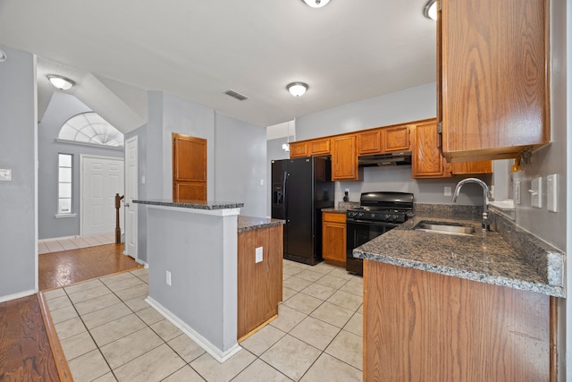 kitchen featuring light tile patterned flooring, dark stone countertops, sink, and black appliances