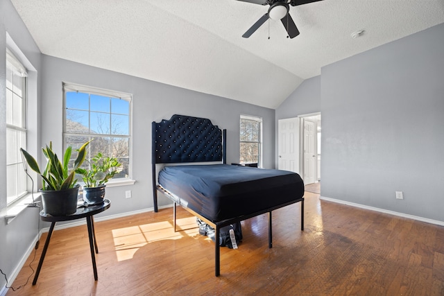 bedroom with ceiling fan, lofted ceiling, hardwood / wood-style floors, and multiple windows