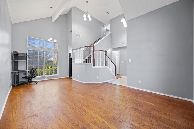 unfurnished living room featuring an inviting chandelier, wood-type flooring, beam ceiling, and high vaulted ceiling