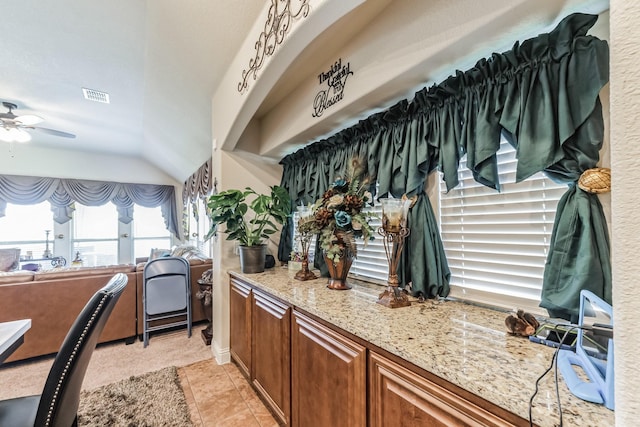 interior space with light stone counters, light tile patterned floors, lofted ceiling, and ceiling fan