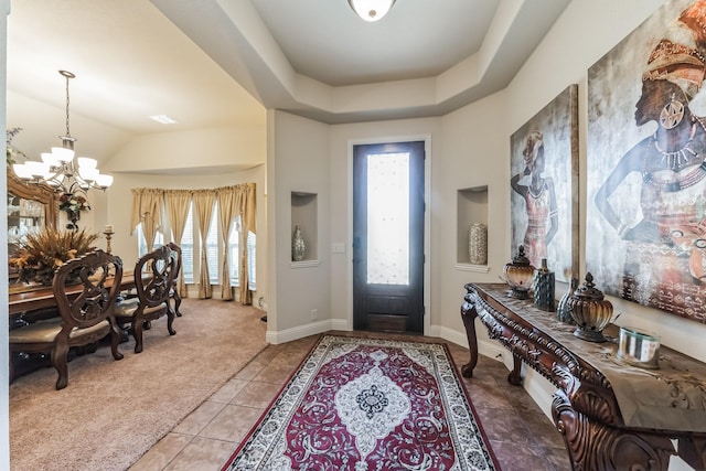 entryway with carpet, a notable chandelier, and a tray ceiling