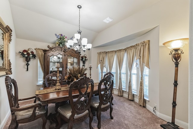 carpeted dining space featuring lofted ceiling and a chandelier