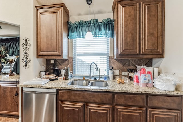 kitchen with sink, tasteful backsplash, hanging light fixtures, stainless steel dishwasher, and light stone countertops