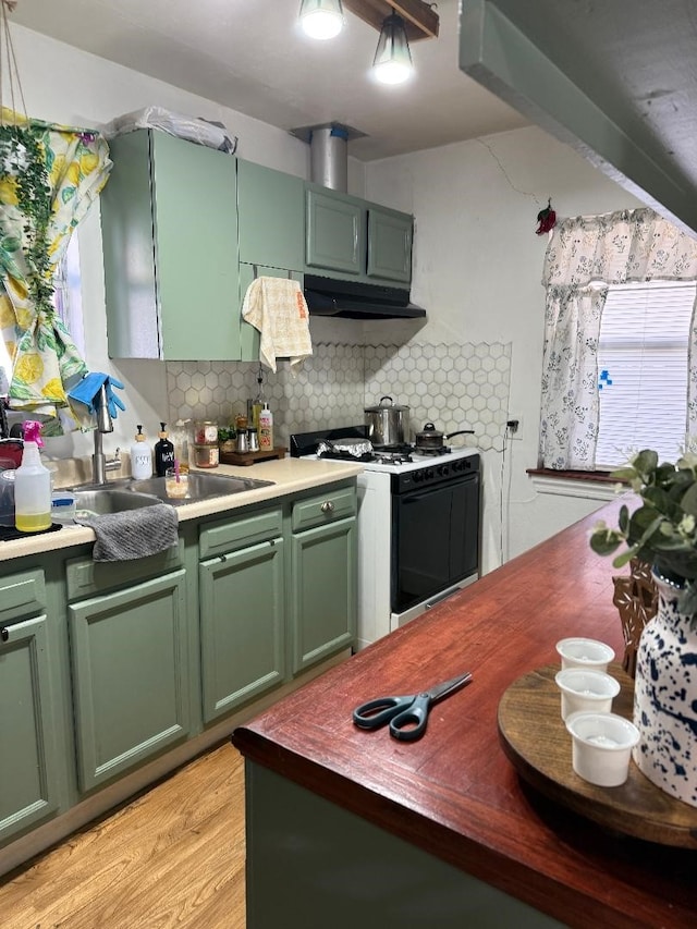 kitchen featuring green cabinetry, gas stove, decorative backsplash, and light wood-type flooring