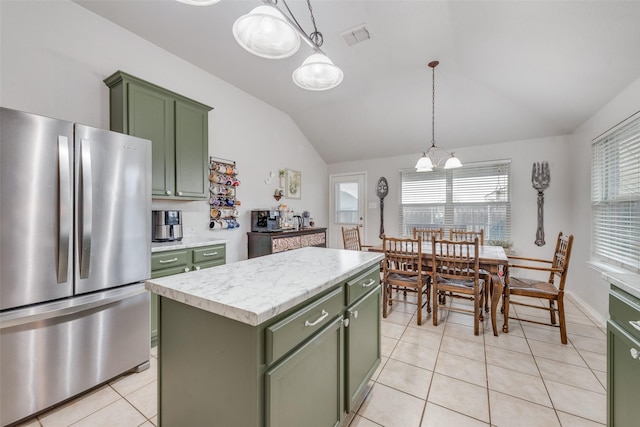 kitchen with lofted ceiling, green cabinetry, hanging light fixtures, stainless steel refrigerator, and a kitchen island