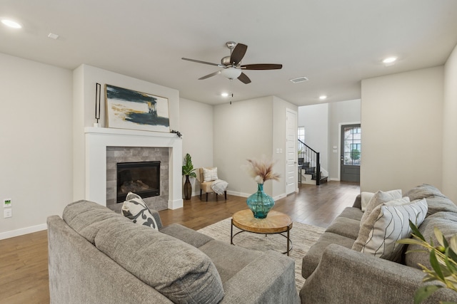 living room featuring a tile fireplace, ceiling fan, and dark hardwood / wood-style flooring