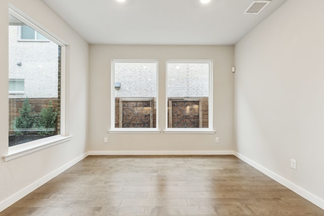 spare room with visible vents, baseboards, and wood finished floors