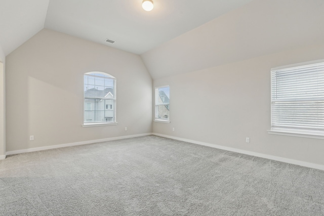 spare room featuring baseboards, visible vents, lofted ceiling, and carpet floors