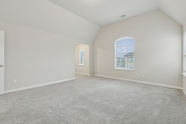 carpeted empty room featuring vaulted ceiling