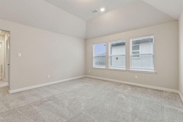 carpeted empty room featuring vaulted ceiling, baseboards, and visible vents