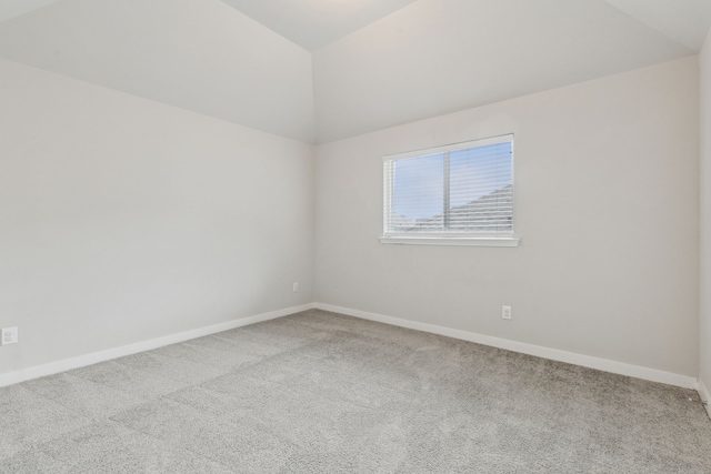 carpeted spare room with baseboards and vaulted ceiling