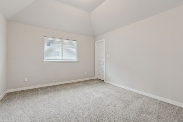 spare room featuring baseboards, carpet flooring, and vaulted ceiling