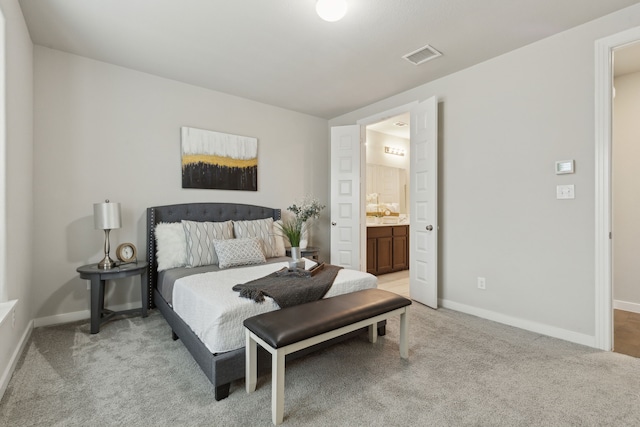 bedroom featuring visible vents, light carpet, baseboards, and ensuite bath