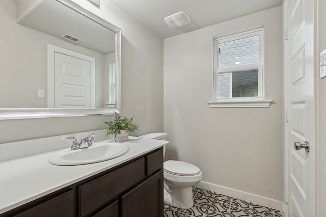 bathroom with visible vents, baseboards, toilet, and vanity