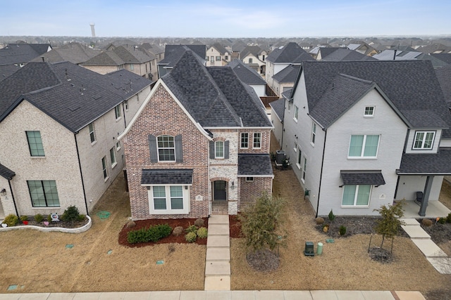 view of front facade featuring a residential view, brick siding, and roof with shingles