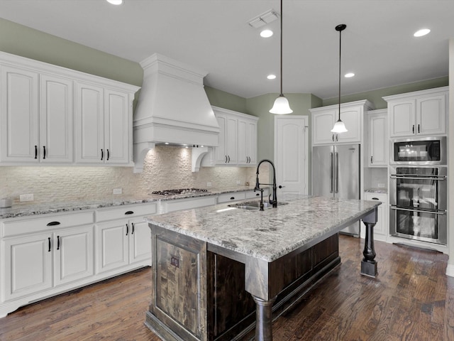 kitchen featuring an island with sink, sink, white cabinets, and light stone counters