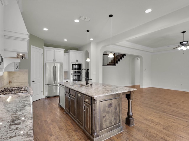 kitchen with sink, light stone counters, dark brown cabinets, stainless steel appliances, and white cabinets