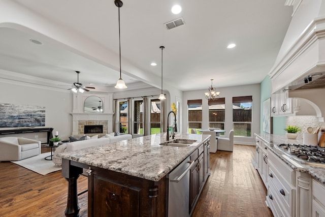 kitchen with hardwood / wood-style floors, a sink, stainless steel appliances, a fireplace, and visible vents