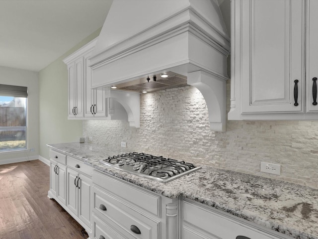 kitchen featuring white cabinets, dark wood-type flooring, stainless steel gas cooktop, tasteful backsplash, and custom range hood