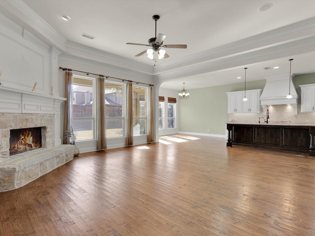 unfurnished living room with a healthy amount of sunlight, a stone fireplace, and hardwood / wood-style floors