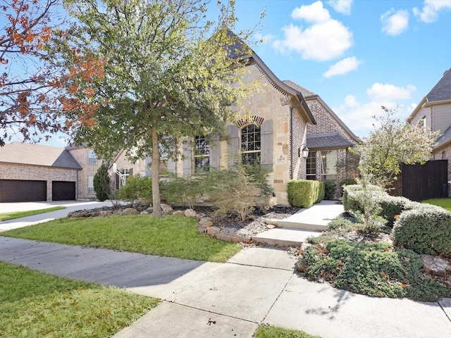 view of front facade featuring brick siding, a front lawn, fence, and stone siding