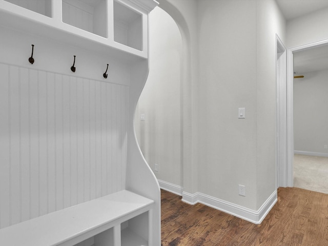 mudroom with arched walkways, wood finished floors, and baseboards