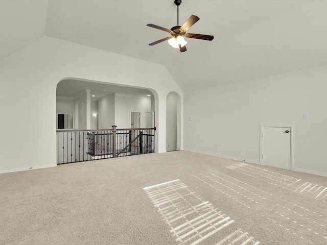 unfurnished room featuring lofted ceiling, carpet, arched walkways, and ceiling fan