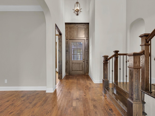 foyer entrance with arched walkways, wood finished floors, and baseboards