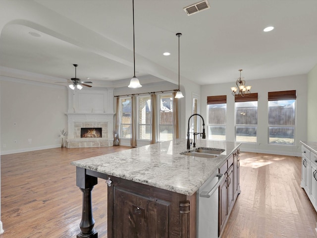 kitchen featuring light stone countertops, sink, white cabinets, and decorative light fixtures