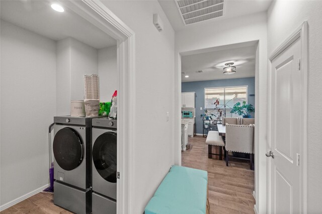 washroom with independent washer and dryer and light hardwood / wood-style floors