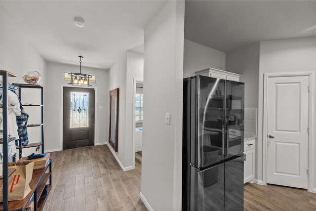 entryway featuring an inviting chandelier and light hardwood / wood-style flooring