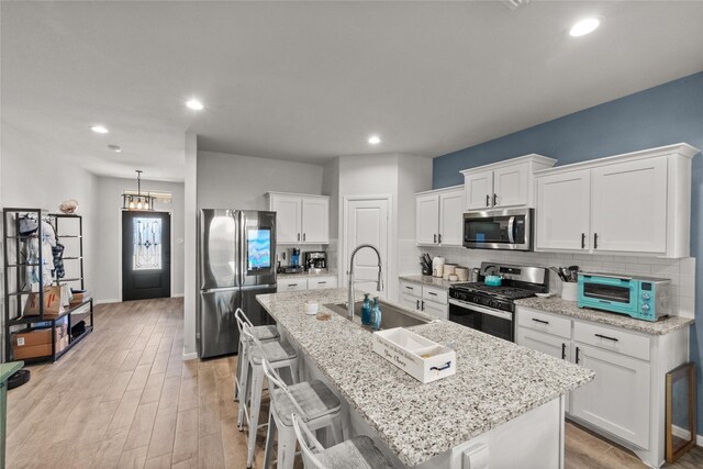 kitchen with a breakfast bar, sink, white cabinetry, an island with sink, and stainless steel appliances