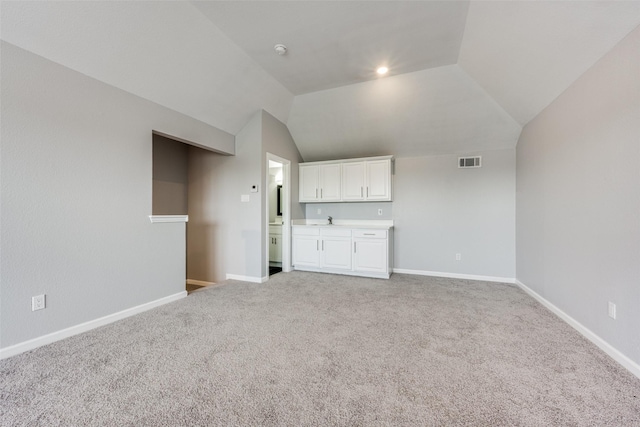 unfurnished living room with sink, vaulted ceiling, and carpet flooring