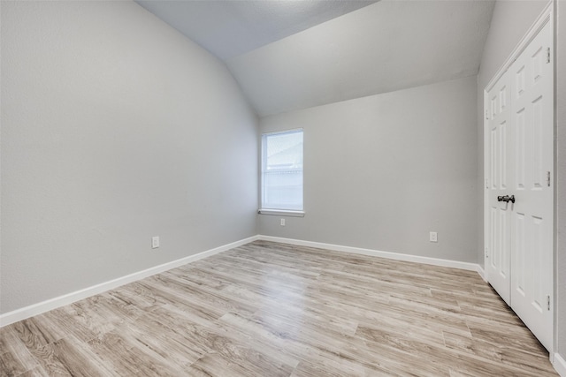 unfurnished bedroom featuring vaulted ceiling, light wood-type flooring, and a closet