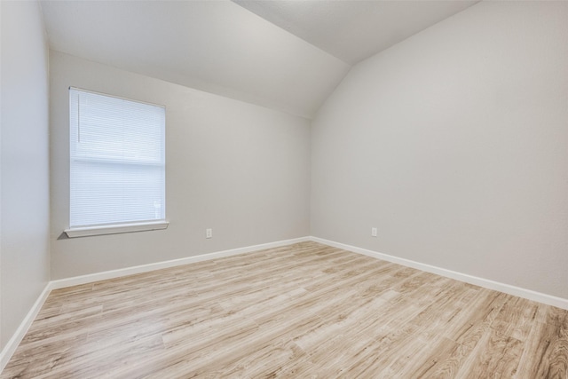 empty room featuring vaulted ceiling and light hardwood / wood-style flooring