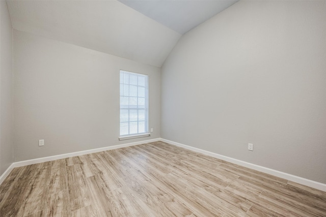 spare room with vaulted ceiling and light hardwood / wood-style floors