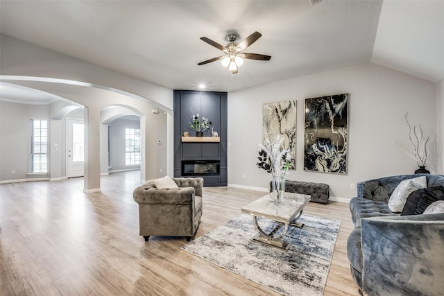 living room with ceiling fan, lofted ceiling, a fireplace, and light hardwood / wood-style flooring