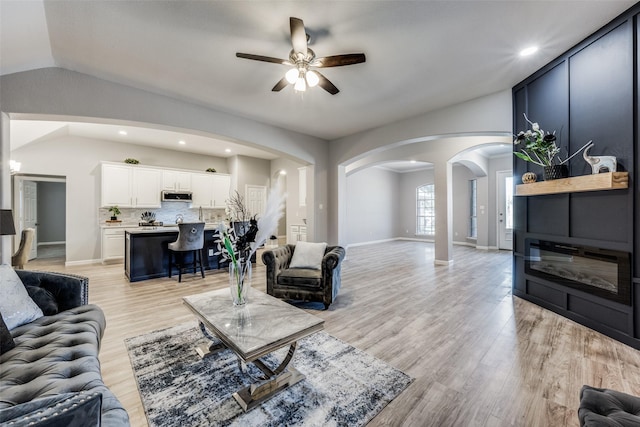 living room with lofted ceiling, ceiling fan, and light hardwood / wood-style flooring