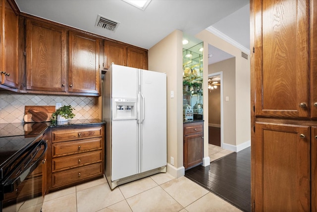 kitchen featuring black range oven, backsplash, white fridge with ice dispenser, light tile patterned floors, and ceiling fan