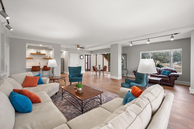 living room featuring light hardwood / wood-style flooring, ceiling fan, and track lighting