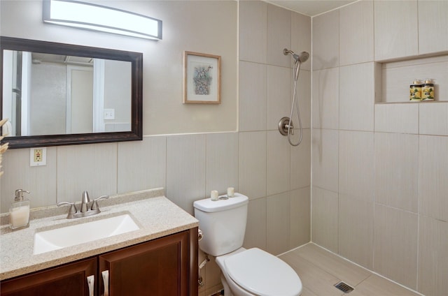 bathroom with vanity, toilet, and a tile shower