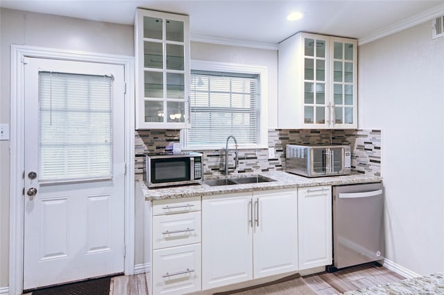 kitchen featuring light wood finished floors, backsplash, appliances with stainless steel finishes, ornamental molding, and a sink